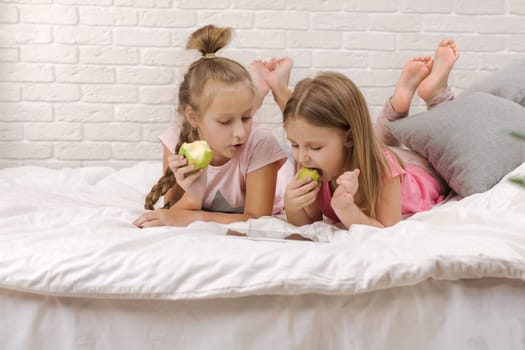two cute children girls use digital tablet in bed. child playing on tablet pc.