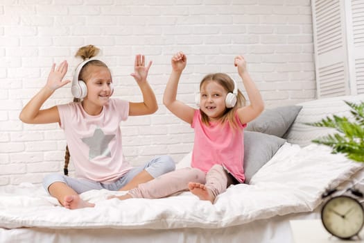 two cute children girls playing in the bedroom. two cute children girls use digital tablet in bed.