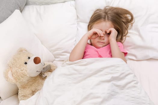 cute little child girl wakes up from sleep in bed in the morning