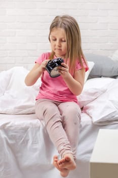 cute little child girl in pyjamas with clock in bed. good morning