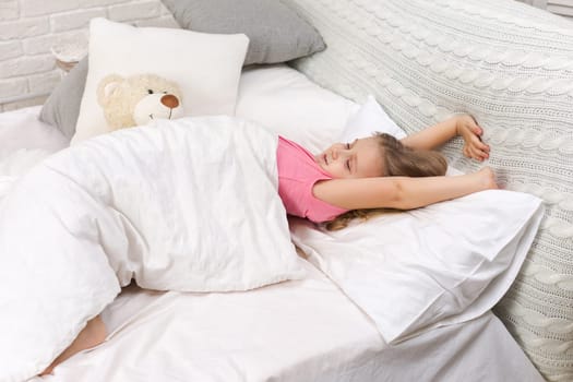 cute little child girl wakes up from sleep in bed in the morning