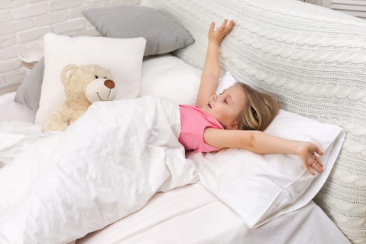cute little child girl wakes up from sleep in bed in the morning