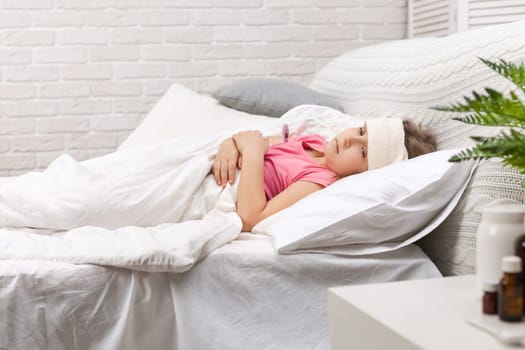 Sick little child girl lying in bed with thermometer. Cold flu season