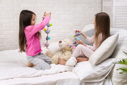 two cute children girls playing in the bedroom. pajama party and friendship.