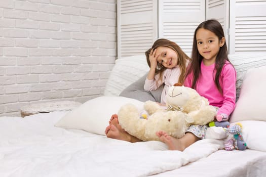 two cute children girls playing in the bedroom. pajama party and friendship.