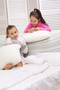 two cute children girls playing in the bedroom. pajama party and friendship.