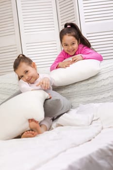 two cute children girls playing in the bedroom. pajama party and friendship.