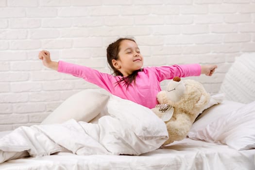 cute little child girl wakes up from sleep and yawns in bed in the morning
