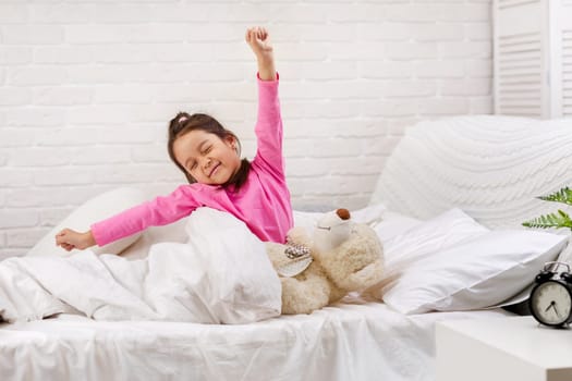cute little child girl wakes up from sleep and yawns in bed in the morning