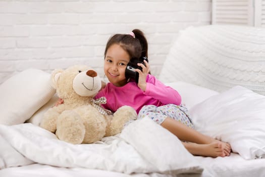 cute little child girl in pyjamas with clock in bed. good morning