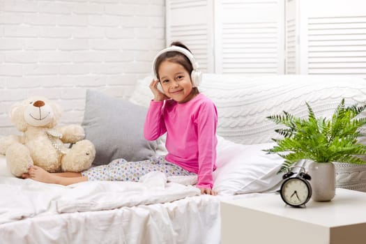 little child baby girl listening to the music with the headphones. happy morning