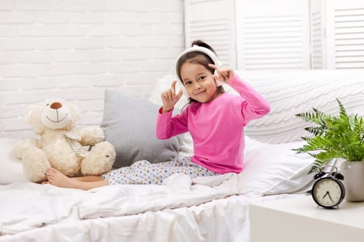 little child baby girl listening to the music with the headphones. happy morning