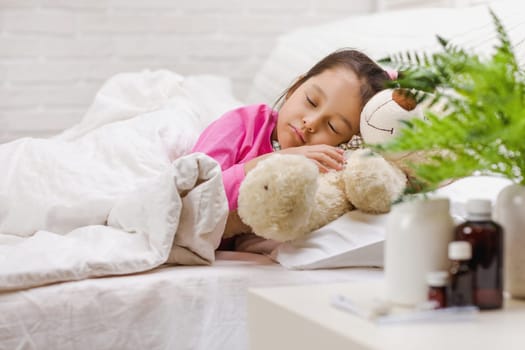 Sick little child girl lying in bed with thermometer. Cold flu season