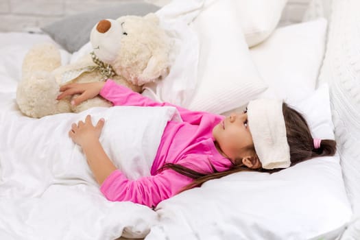 sick cold little child girl lies in bed with fever