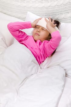 sick cold little child girl lies in bed with fever
