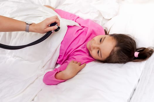 Pediatrician checks breath stethoscope a little girl