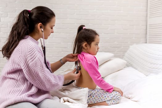 hand of doctor with stethoscope listening to child back. Pediatrician checks breath stethoscope a little girl