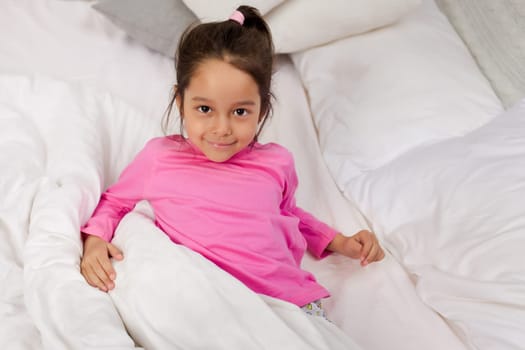 adorable little child girl smiling after waking up in bed