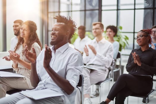 Large group of happy entrepreneurs applauding on a business seminar in a board room.
