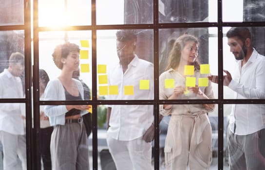 colleagues discuss and stick notes on the glass in the office