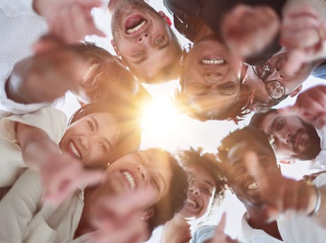 group of diverse young people standing in a circle and looking down