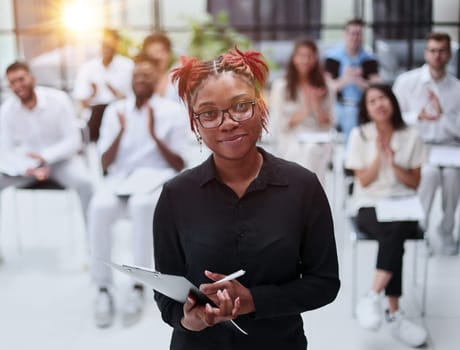 african american woman with a notepad against the background of other people at the seminar. business concept