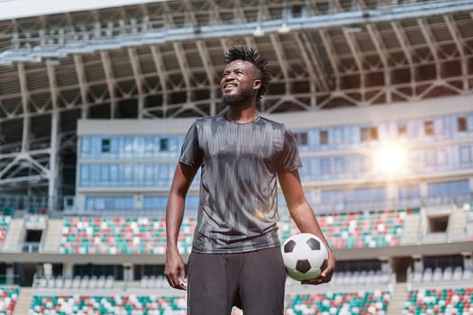 confident black football player holding the ball in his hand