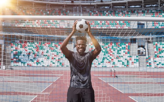 african american football player holding the ball in his hands at the stadium
