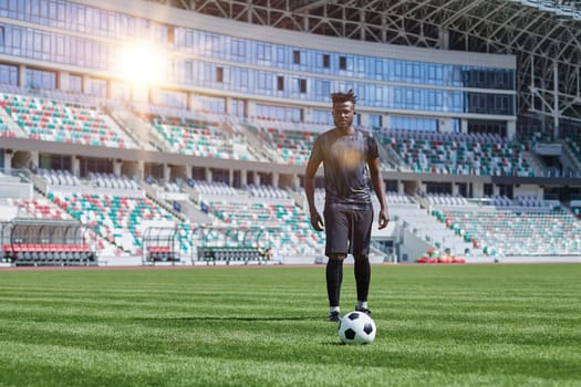 African American man playing football on the stadium field.