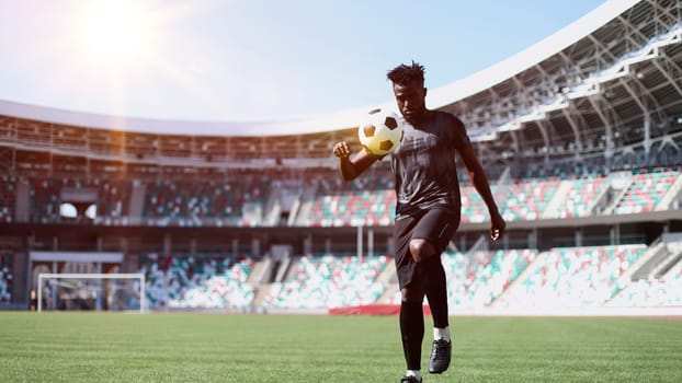 African American man playing football on the stadium field.