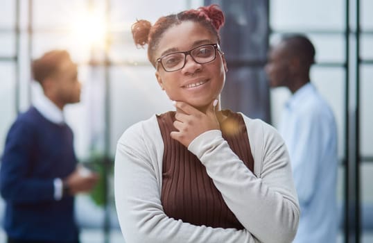 Smiling young woman standing with her arms crossed and looking at camera.