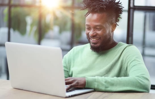 Young african american business man sitting in loft office or cafe, working on new online IT startup project, using laptop