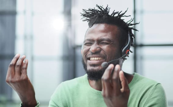 Operator of hot line. Portrait of cheerful african customer service representative with headset in call center, empty space