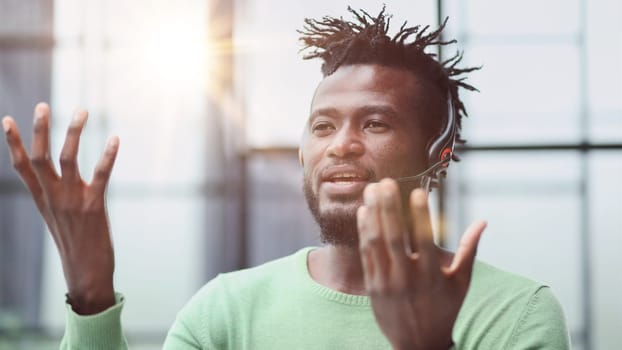 Operator of hot line. Portrait of cheerful african customer service representative with headset in call center, empty space