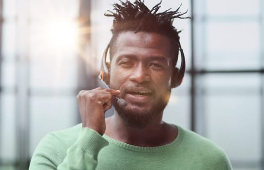 Operator of hot line. Portrait of cheerful african customer service representative with headset in call center, empty space
