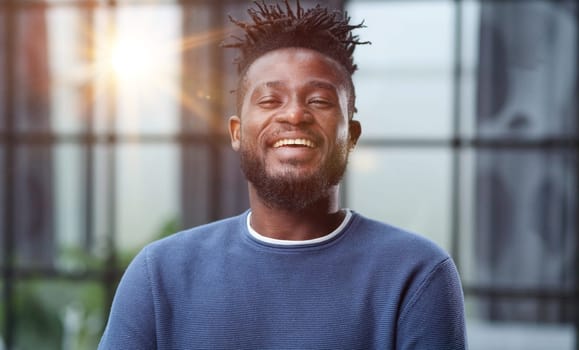 Handsome charming cheerful african american businessman in chic colorful casual clothes, in an office building