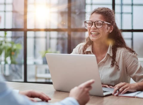 manager in glasses sitting at the table receives a client in the office looking at the camera