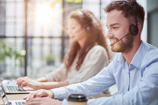Handsome male customer service agent working in call center office as a telemarketer.
