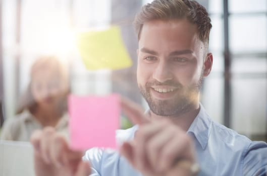 businessman is working on a project. Business man pointing at a note on the glass wall