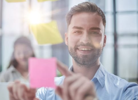 businessman is working on a project. Business man pointing at a note on the glass wall