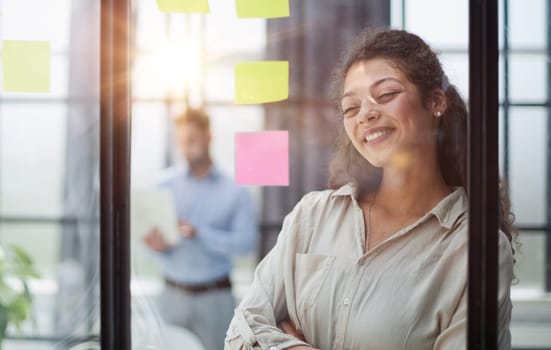 Bringing her vision to life. Shot of a confident businesswoman presenting an idea to her colleague using adhesive notes on a glass wall in the office.