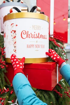 A girl on the street in red gloves holds a big red box in her hands. Christmas and New Year