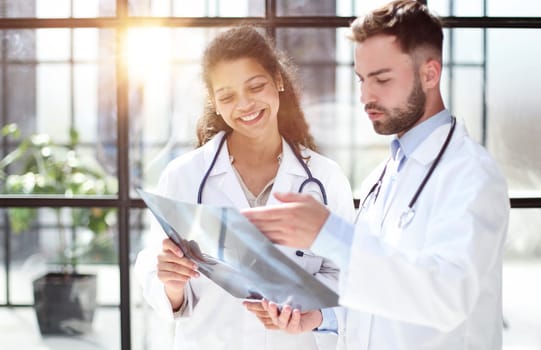 Two busy doctors working with papers and x-rays in hospital lobby