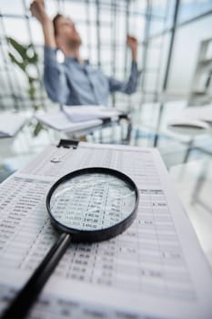 Magnifying glass and documents with analytics data lying on table,selective focus