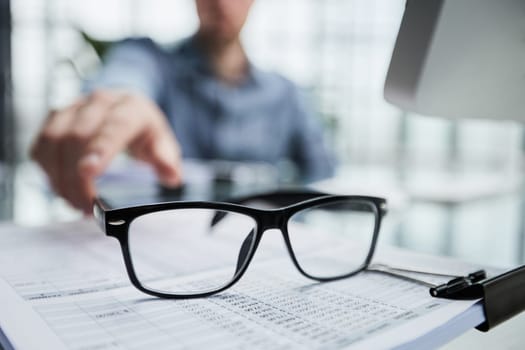 Businessman looking through a magnifying glass to documents note in the office.