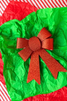 Very beautiful shiny red bow lying on gift paper, concept of gift wrapping and Christmas and New Year celebration. View from above