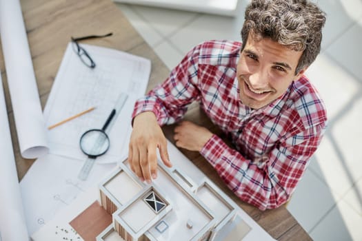 Male architect holding and working on model of architectural house top view