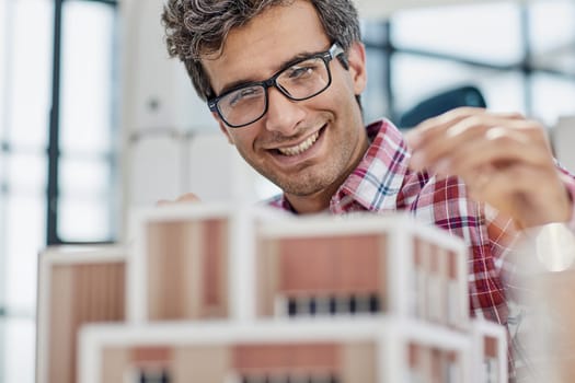 Young businessman or architect with model of a house standing in office, working.