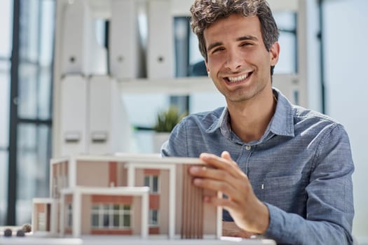 young caucasian engineer man making building model with the use of drawings and notes in office. smart designer assembles a complex structure