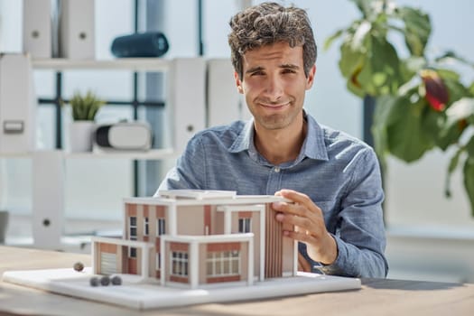 young caucasian engineer man making building model with the use of drawings and notes in office.